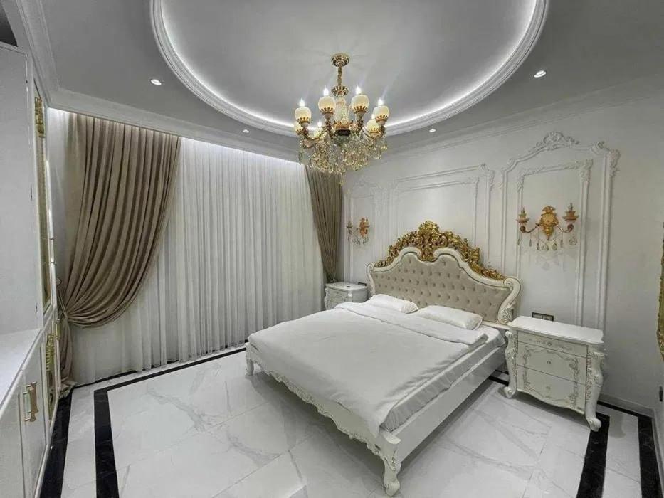 een slaapkamer met een groot bed en een kroonluchter bij Premium Residences by Renowned Builders in Tasjkent