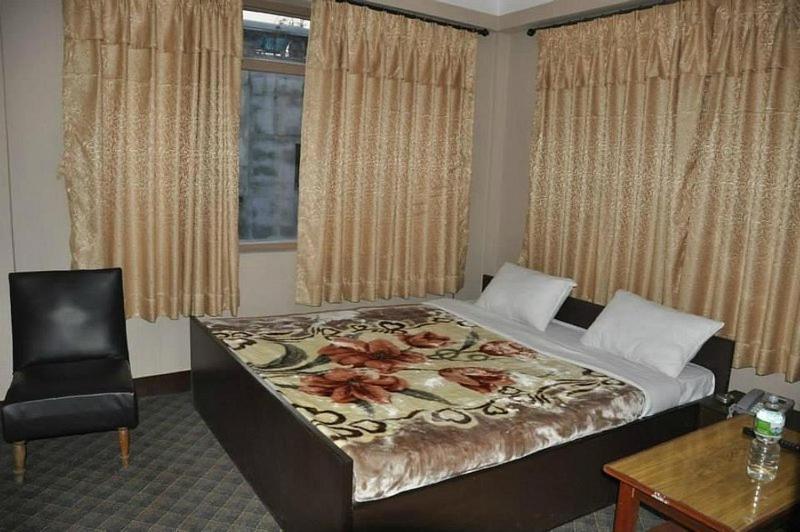 um quarto com uma cama, uma cadeira e uma janela em International Hotel Appt em Kathmandu