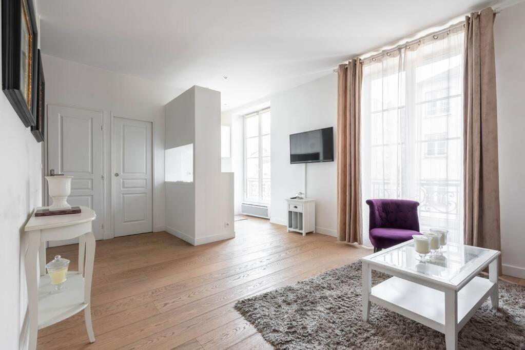 ein weißes Wohnzimmer mit einem lila Stuhl und einem Tisch in der Unterkunft Appartement Vintage Le Bon Marché - III in Paris
