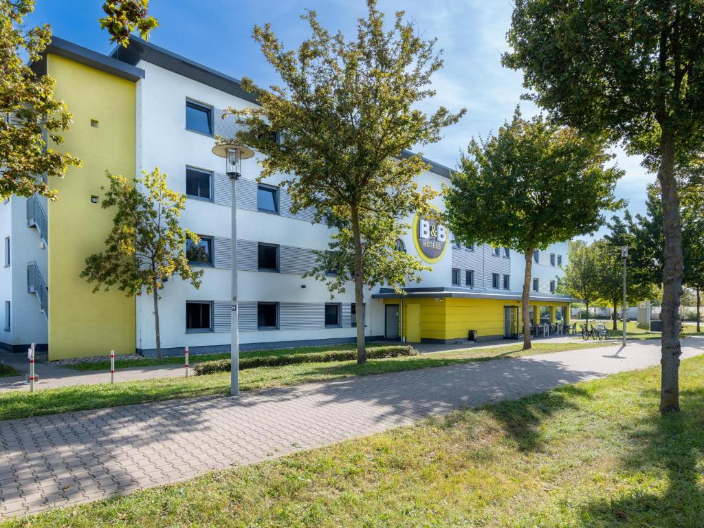 een groot wit gebouw met bomen ervoor bij B&B Hotel Mannheim in Mannheim