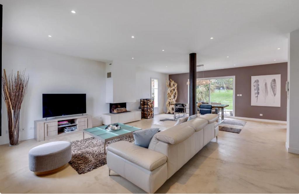 ein Wohnzimmer mit einem Sofa und einem TV in der Unterkunft Olympic Games - Exclusive House in Villennes-sur-Seine
