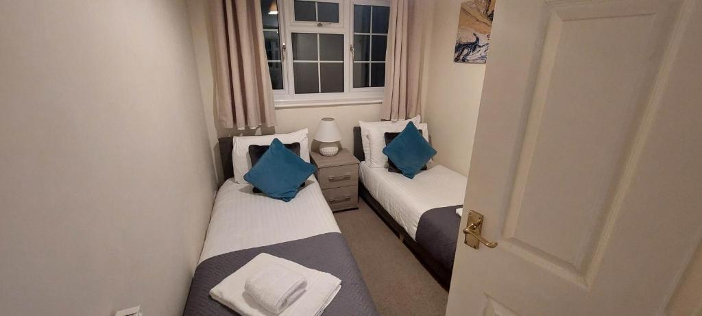 two beds in a small room with blue pillows at Charming 3 Bed house Family and Long-stay Discount in Maidenhead