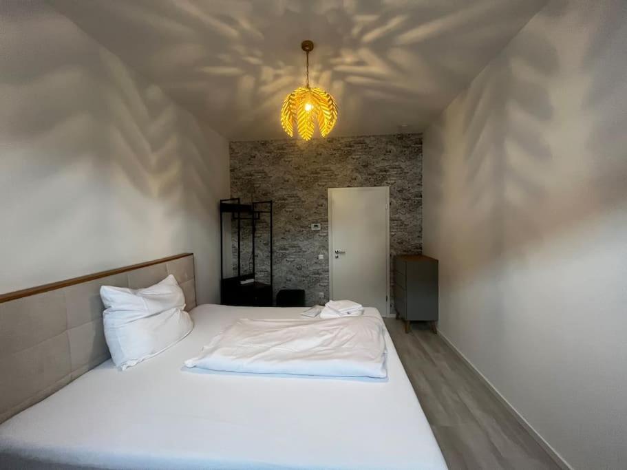 a bedroom with a white bed and a chandelier at Lisboa: Messe/Business/FeWo DUS in Hilden