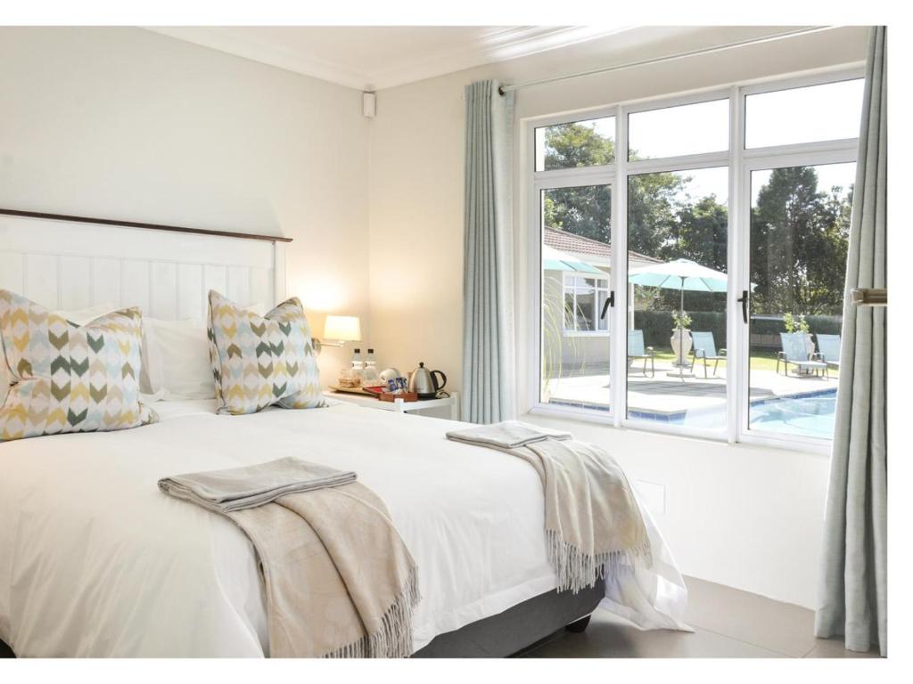 a white bedroom with a bed and a large window at 66 On Monzali 4 Star Luxury Guesthouse in Hilton