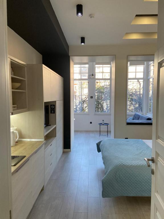 uma cozinha com armários brancos e uma cama num quarto em Boulevard Apartments em Sarajevo