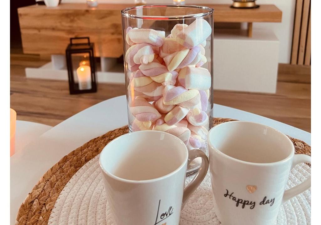 a vase filled with marshmallows and two cups on a table at Te Dua-room - Le Barcares in Le Barcarès