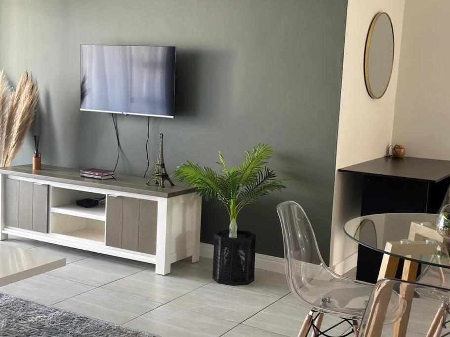 a living room with a tv and a table with a plant at Apartment in Kikuyu, Waterfall in Midrand