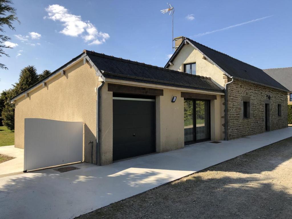 una casa con dos puertas de garaje y un camino de entrada en La hantelle, en Saint-Hilaire-des-Landes