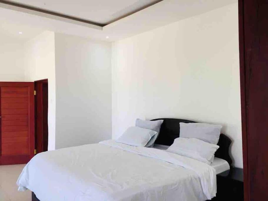 um quarto com uma cama com lençóis brancos e almofadas em Executive 4 bedroom house with 4 beds . em Lusaka