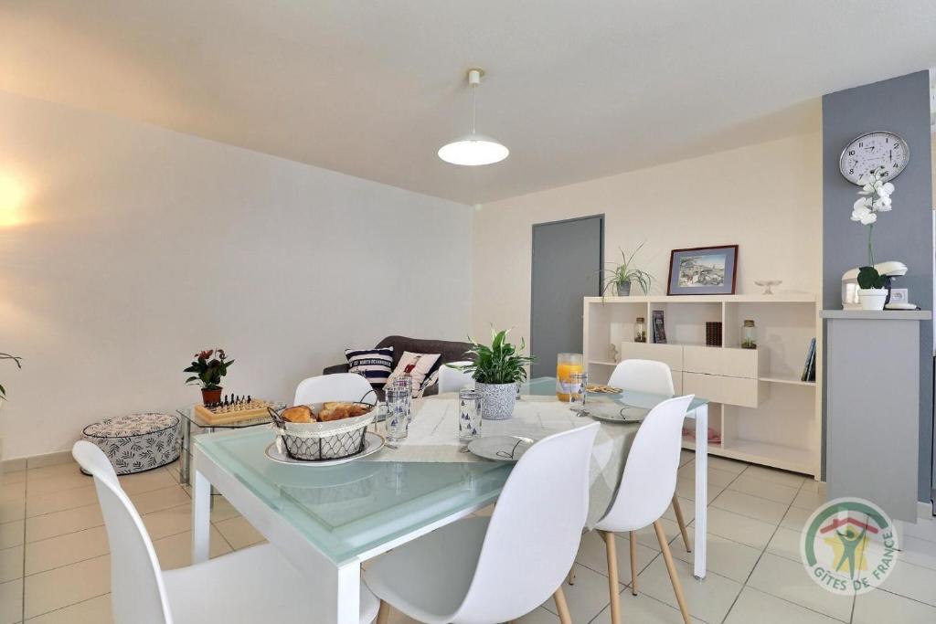 comedor con mesa de cristal y sillas blancas en Le balcon de sevigne, en Cesson-Sévigné