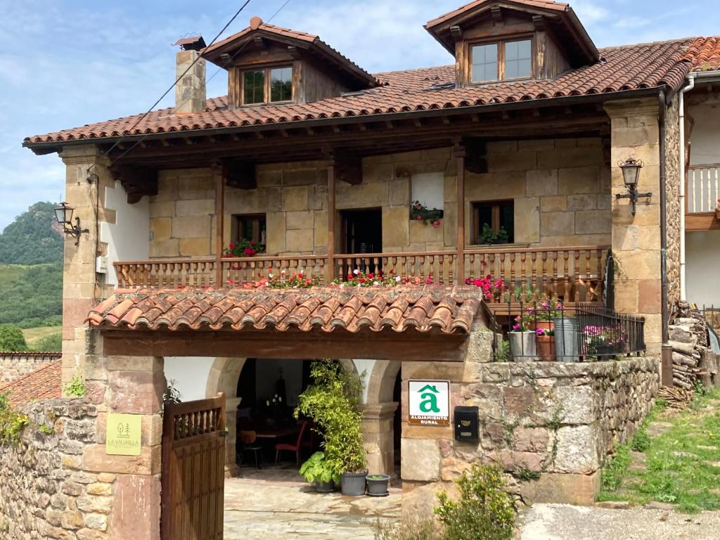Casa de piedra antigua con balcón y puerta en La Valuisilla, hotel rural en Cicera