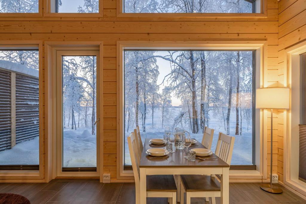 una sala da pranzo con tavolo e sedie e una grande finestra di Miilu Resort a Ylläsjärvi