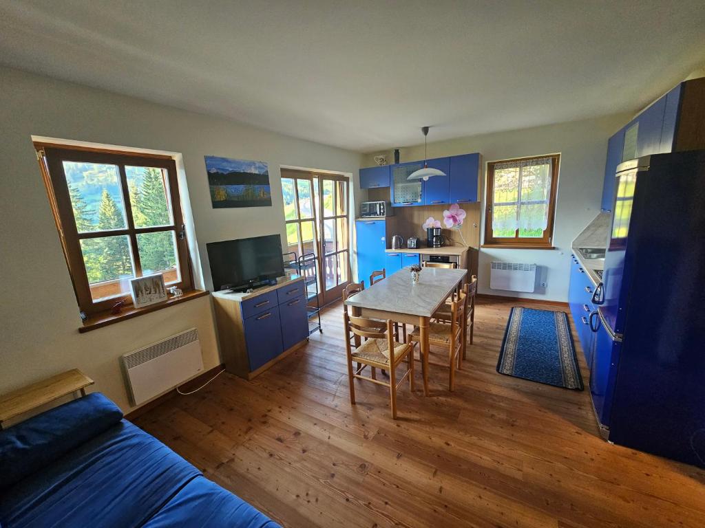 a living room with a table and a kitchen with blue cabinets at Top location ski-to-door two-bedroom apartment in Bach