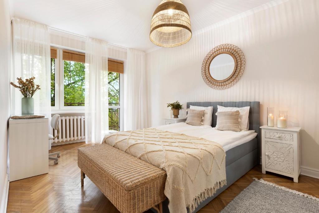 a white bedroom with a large bed and a mirror at Elite Apartments Marine Brzeźno in Gdańsk