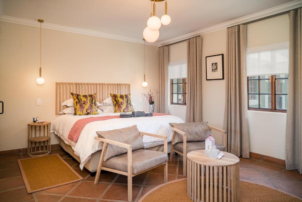 a bedroom with a large bed and chairs in it at The Lofts @ Maple Square in Dullstroom