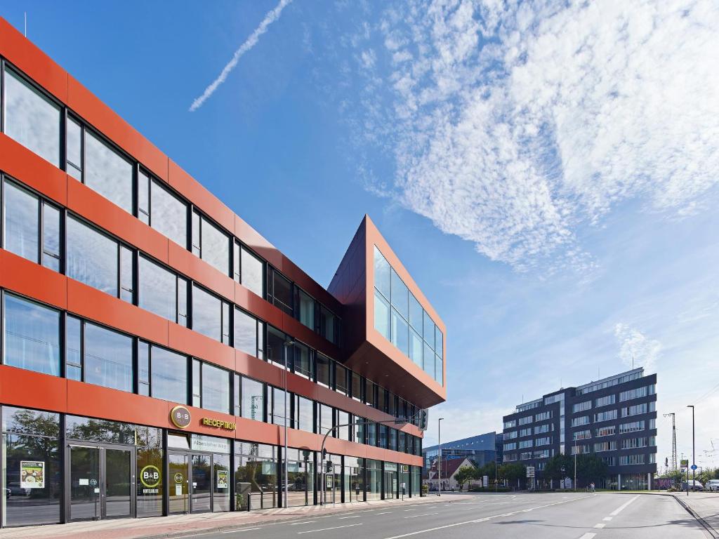 un edificio de oficinas con una fachada roja y negra en B&B HOTEL Münster Hafen en Münster