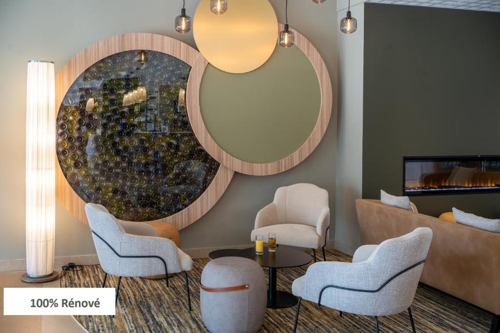 a lobby with chairs and a table and a mirror at Mercure Auxerre Autoroute du Soleil in Appoigny