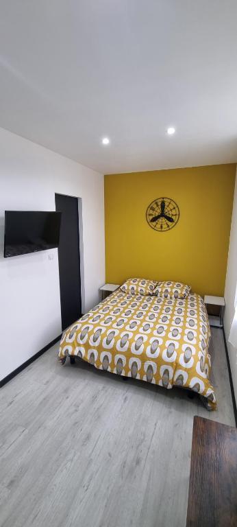 Studio Orchidée, tout confort, rénové في سانت كونتان: غرفة نوم بسرير وجدار اصفر