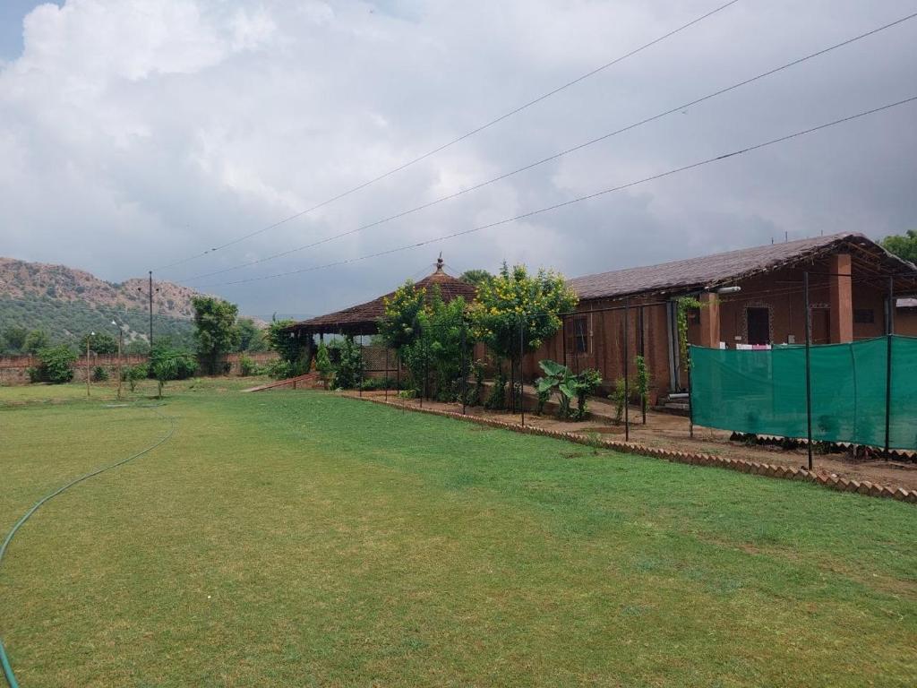 a house with a green fence in front of a yard at Gramya Resort in Alwar