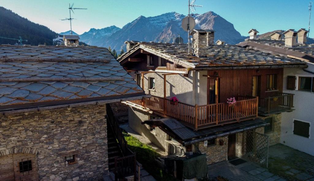 een oud huis met een balkon en bergen op de achtergrond bij Baita Plagnol Sestriere Ski Slopes in Sestriere