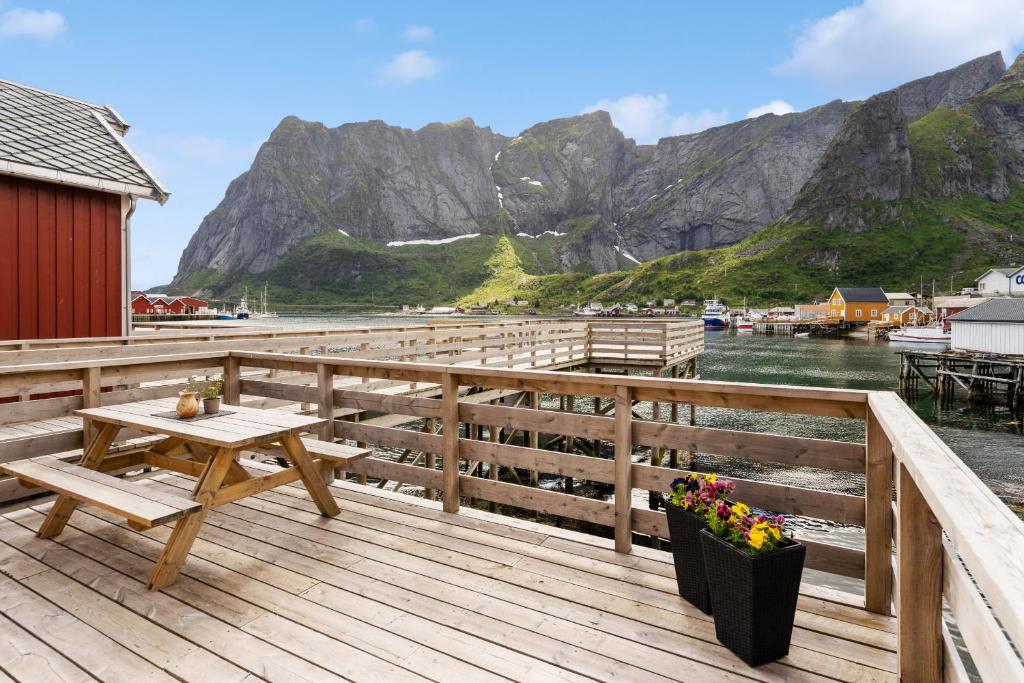 a wooden deck with a picnic table and mountains at Reine Rorbu, Amaliebua in Reine