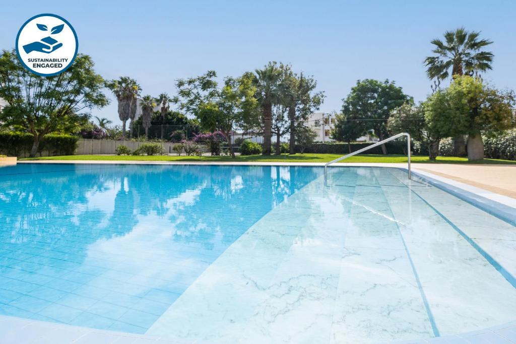a swimming pool with blue water and trees at Apartment Santorini by Algarve Vacation in Alvor