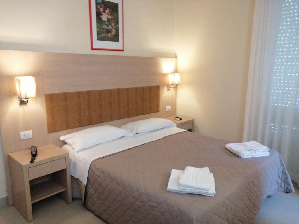 Hotel Cuba Aeroport Restaurant في ريميني: غرفة فندق عليها سرير وفوط
