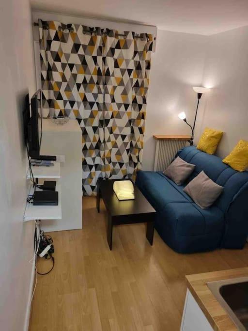 un salon avec un canapé bleu et une télévision dans l'établissement Mignonnette, à Paris