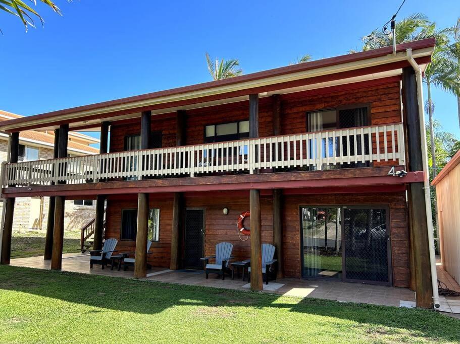 een groot houten huis met een balkon en stoelen bij Beachside Modern Cedar Home in Emu Park