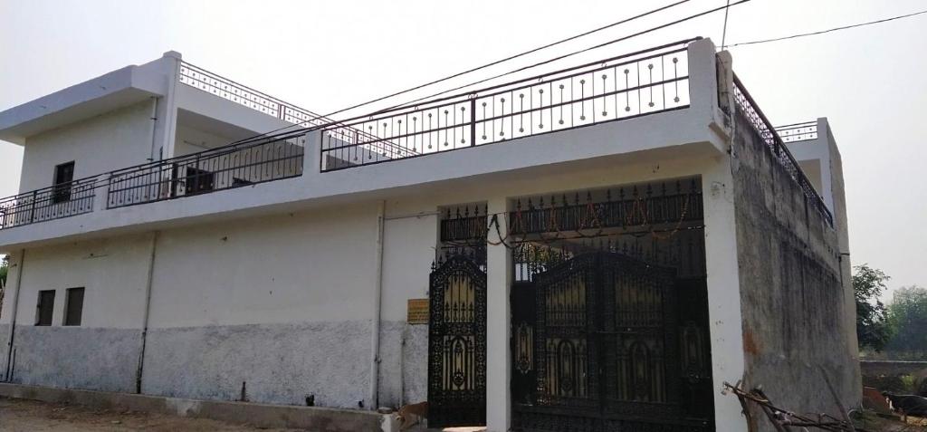 un edificio blanco con una puerta y una valla en Krishna dhaam bungalow Goverdhan, Mathura, en Rādha Kund
