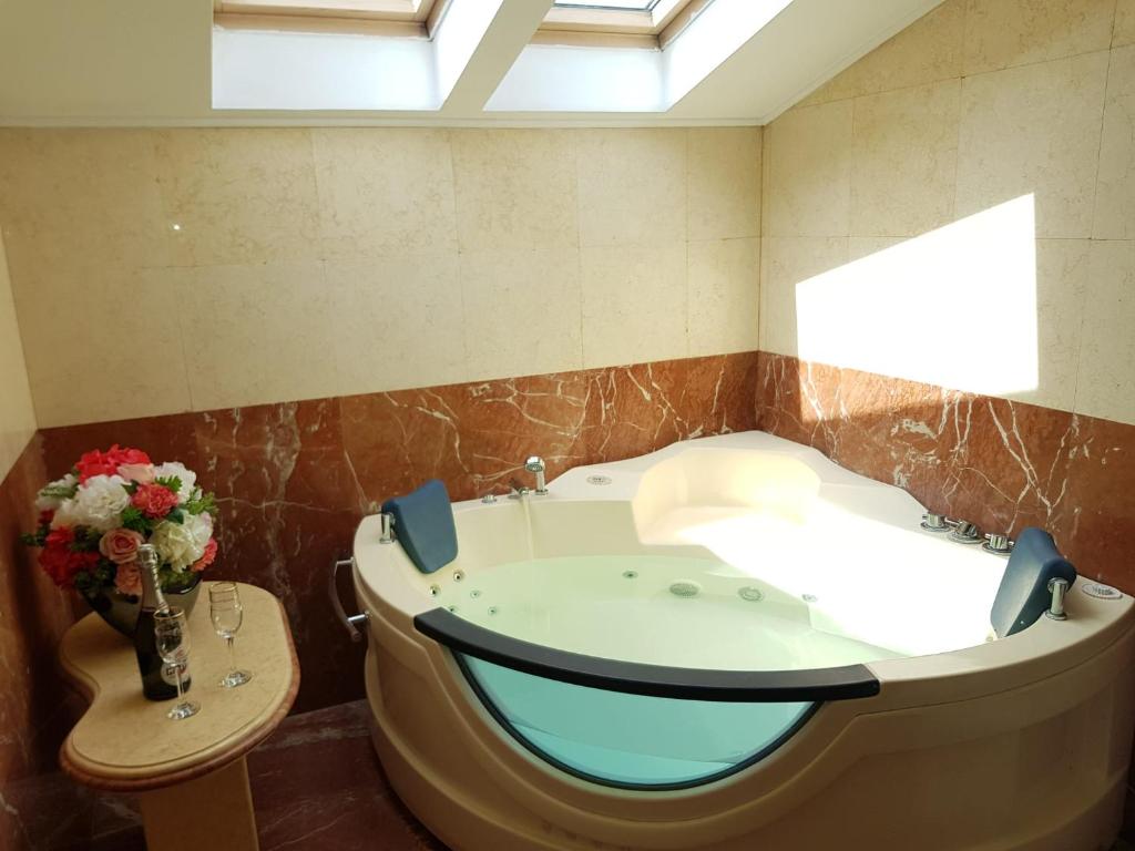 La salle de bains est pourvue d'une baignoire et d'un vase de fleurs. dans l'établissement Open Space Spa Apartment Monza National Arena, à Colonişti