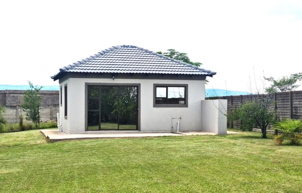 een klein huis met een groot raam in een tuin bij Bakoena's full house in Newcastle