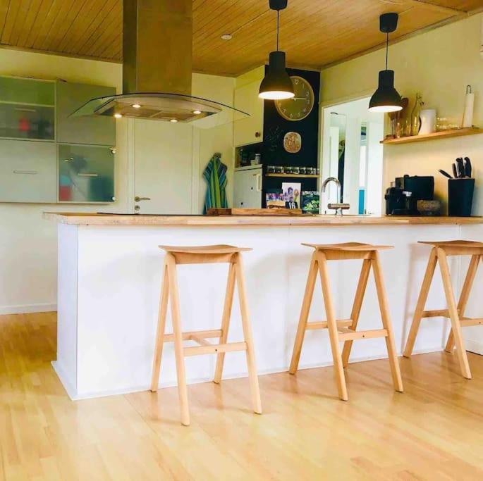 a kitchen with a white counter with two stools at COZY HOLIDAY HOME by the sea in Yderby