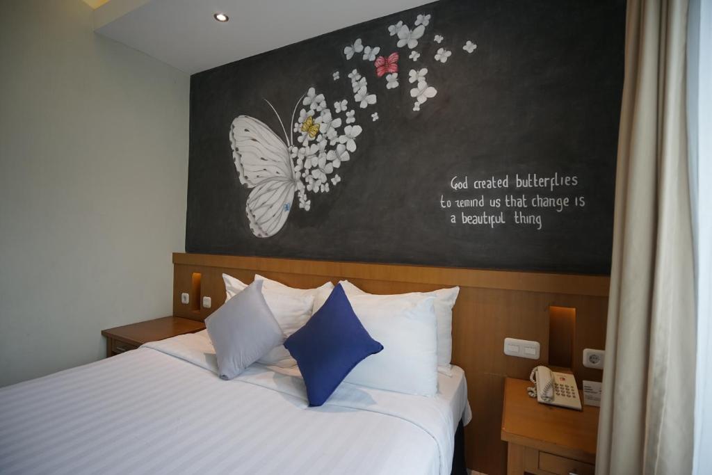 a bedroom with a bed with a butterfly painting on the wall at Hotel Sriti Magelang in Magelang