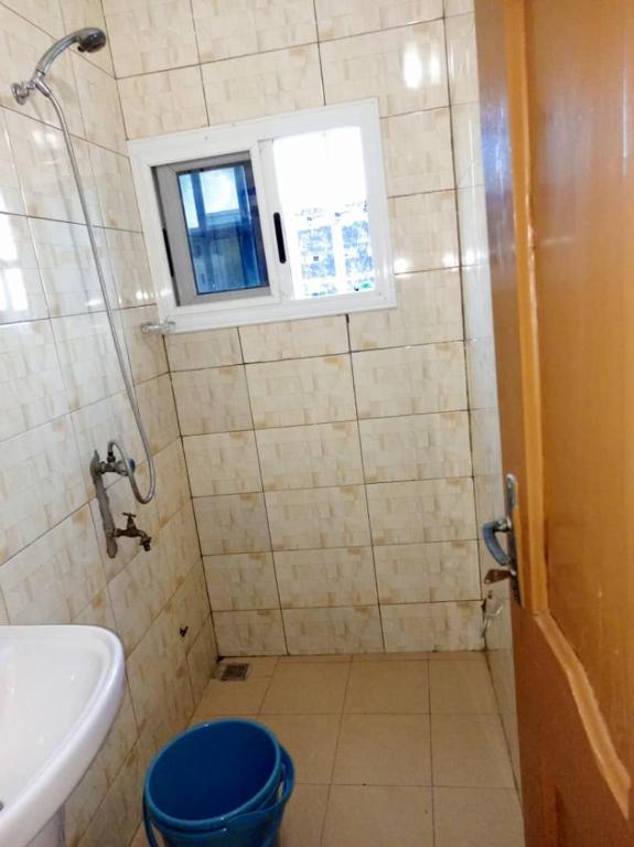 baño con aseo y lavabo y ventana en Appartement Aéroport 2, en Lomé