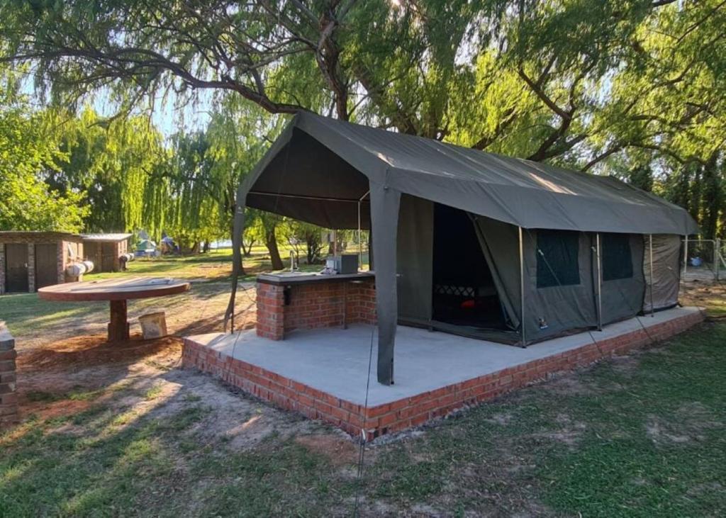 a tent with a picnic table in a park at Riverbend Camp - Self-catering Luxury Glamping Tent in Christiana