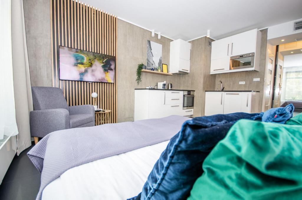 a bedroom with a bed and a chair and a kitchen at InPoint Apartments G13 near Old Town & Kazimierz in Kraków