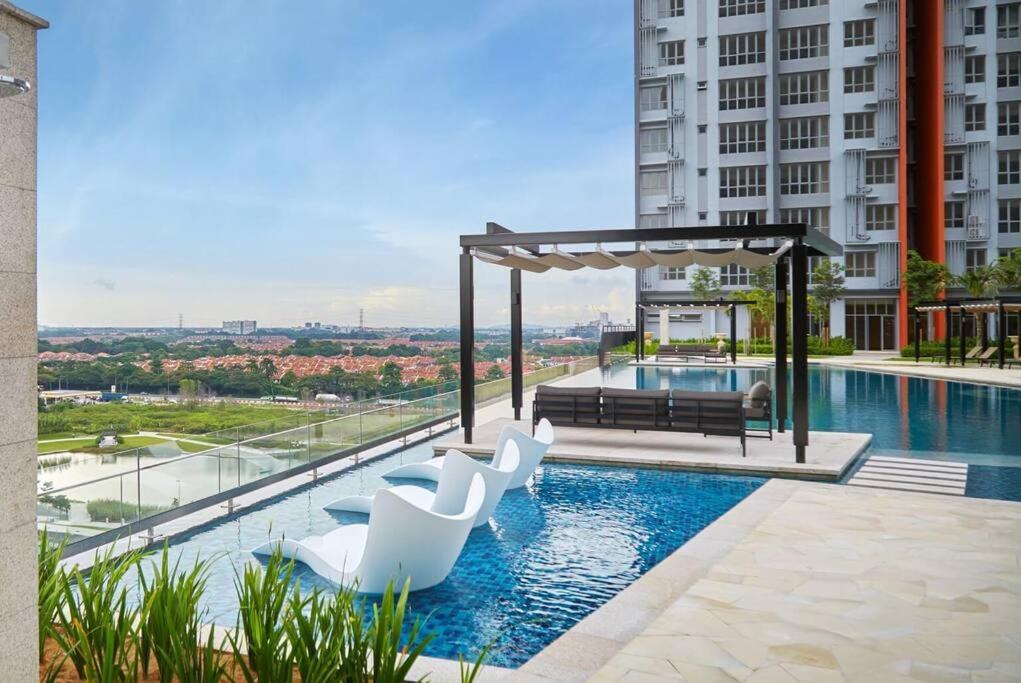 a swimming pool with white chairs and avisor at Condo in Klang. Nordica Gravit8 in Klang