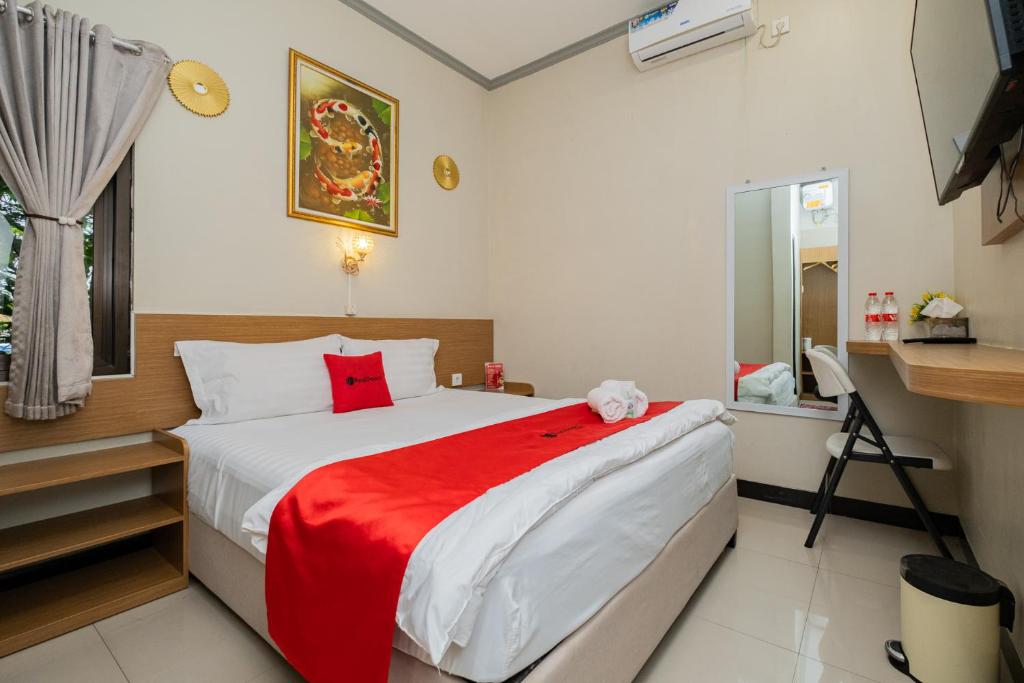 een slaapkamer met een bed met een rode deken bij RedDoorz near Kampung Inggris Pare in Pare