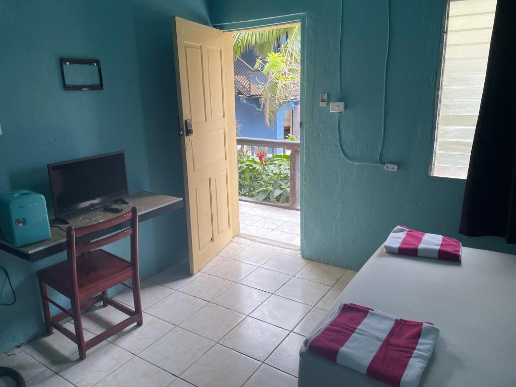 a room with a bed and a desk with a computer at Airport Inn Roatan in Coxen Hole