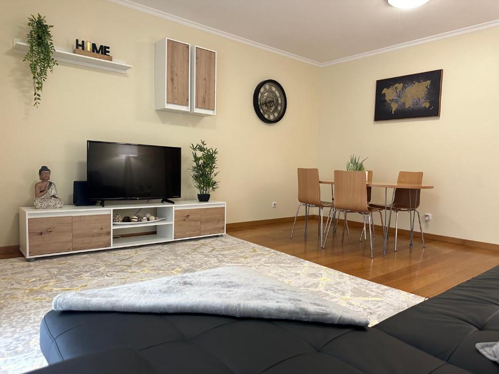 ein Wohnzimmer mit einem Flachbild-TV und einem Tisch in der Unterkunft Lido View Holiday Apartment in Funchal