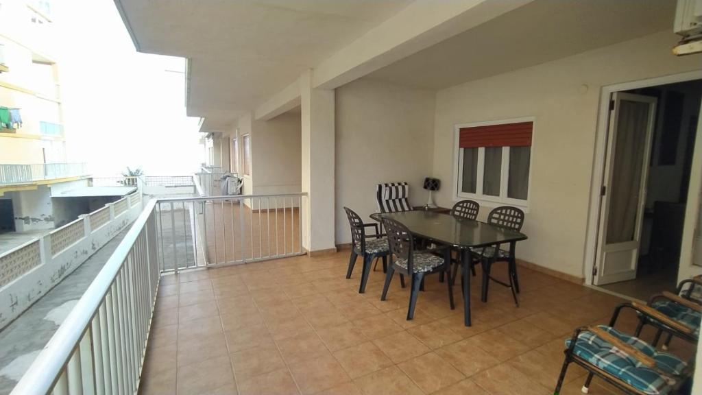 una sala da pranzo con tavolo e sedie sul balcone di Sencillo apartamento en primera línea de playa a Tavernes de Valldigna