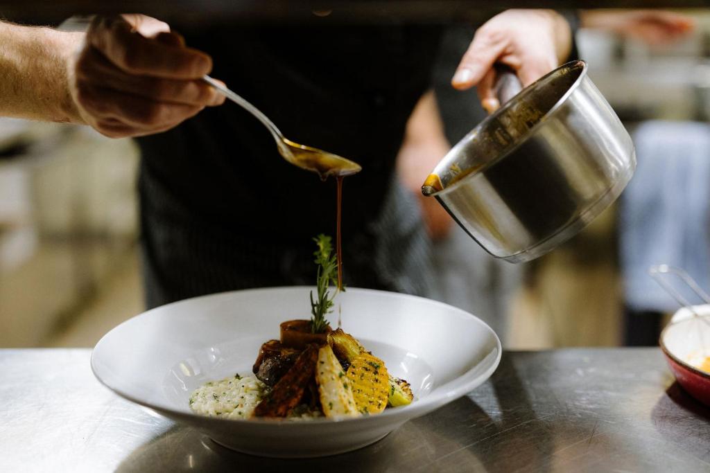 a person is pouring sauce into a bowl of food at Alpine Hotel Perren in Zermatt