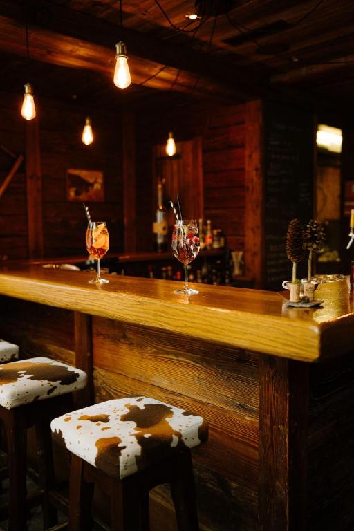 a bar with two wine glasses and two stools at Alpine Hotel Perren in Zermatt