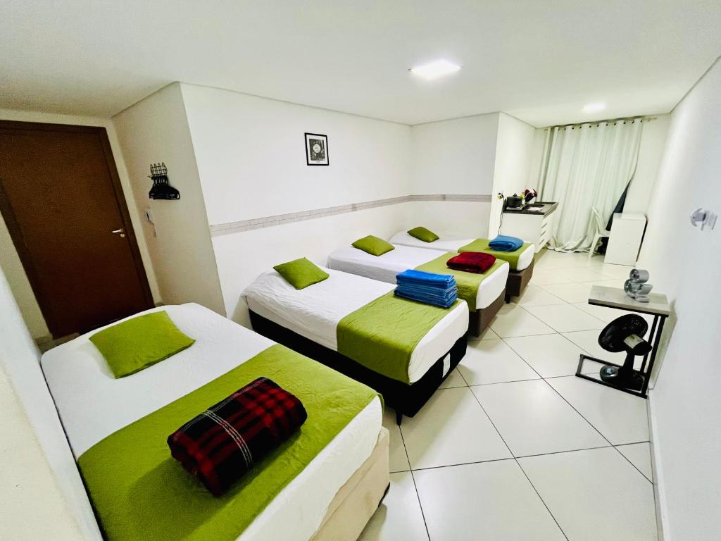 a hotel room with three beds in it at Flat Gru in Guarulhos