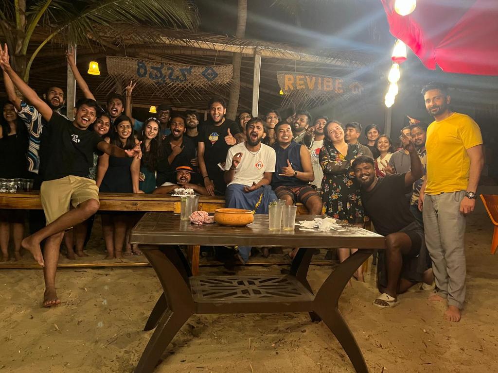 a group of people posing for a picture at a table at Revibe Beach Hostel Gokarna in Gokarna