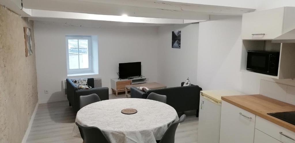 eine Küche und ein Wohnzimmer mit einem Tisch und Stühlen in der Unterkunft Appartement 2 chambres in Champdeniers