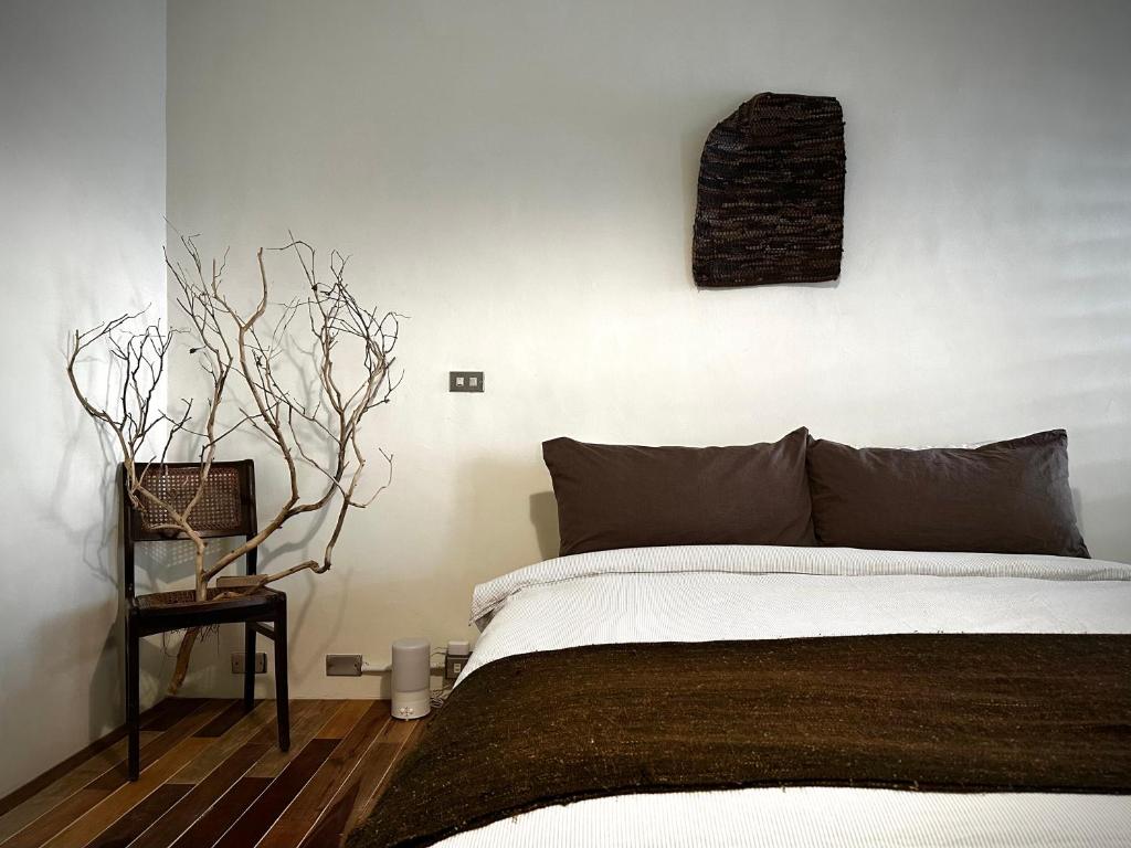 1 dormitorio con 1 cama y un árbol en la pared en 仨食居室, en Hengchun