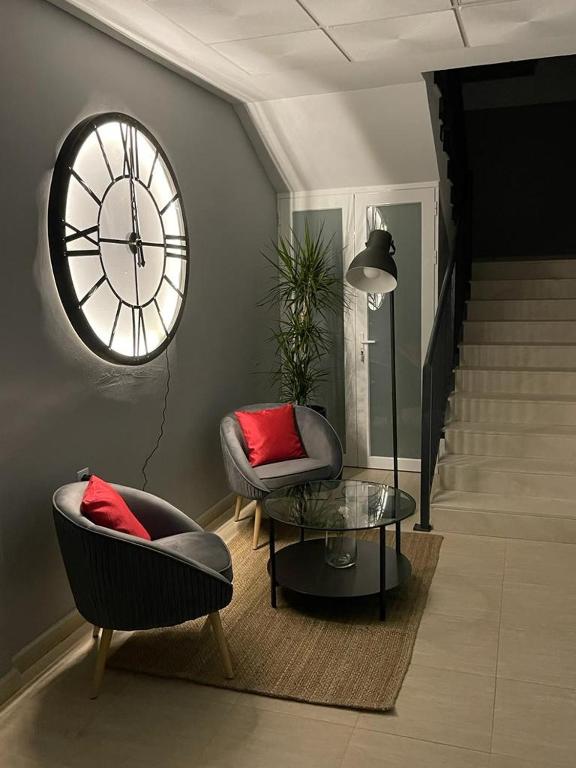 a living room with two chairs and a clock on the wall at La Antigua Editorial in Pozuelo de Zarzón