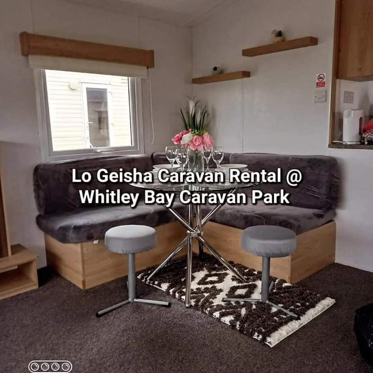 a living room with a black couch and two stools at Lo Geisha Caravan Rental at Whitley Bay Caravan Park in Whitley Bay